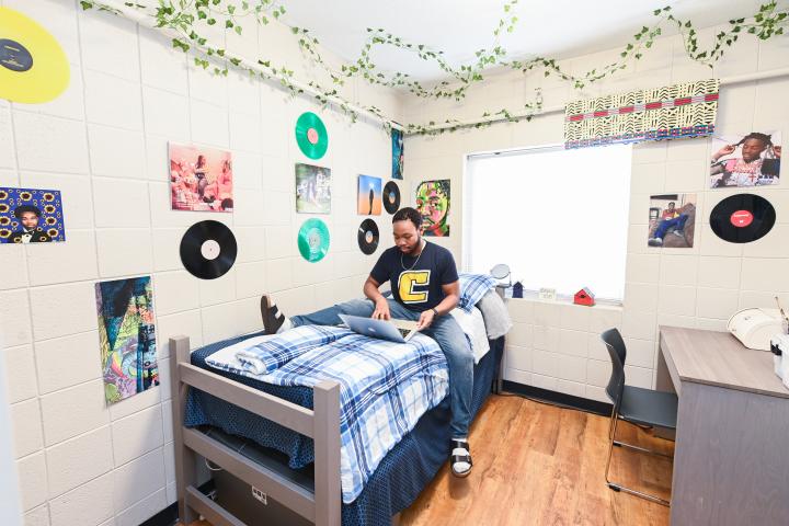 male resident sitting in on-campus bedroom