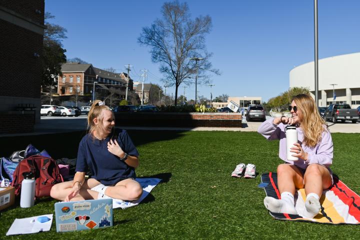 two girls sitting outside in west campus courtyard