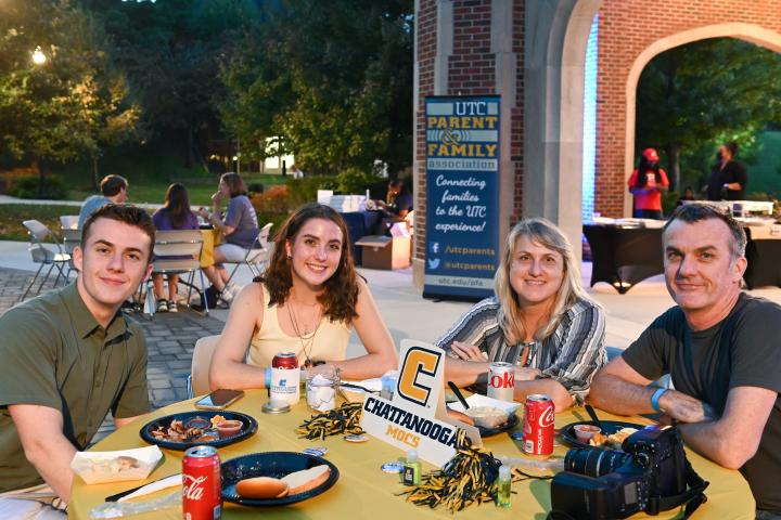 A family attending Fall Family Weekend poses for a photo during dinner. 