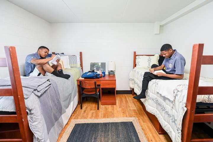 two male students on the beds in residence hall bedroom
