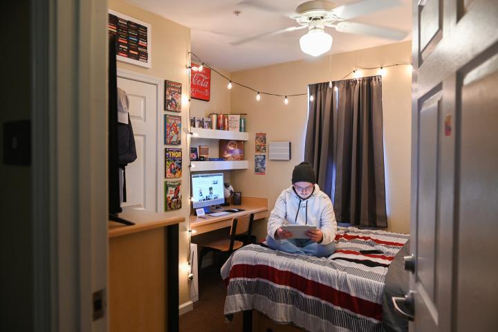 Male student on bed looking at tablet