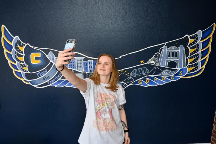 Student in front of a mural