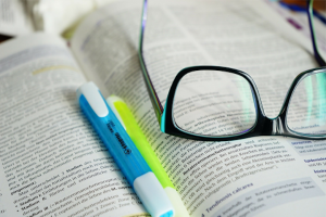 prescription glasses and highlighters on an open book